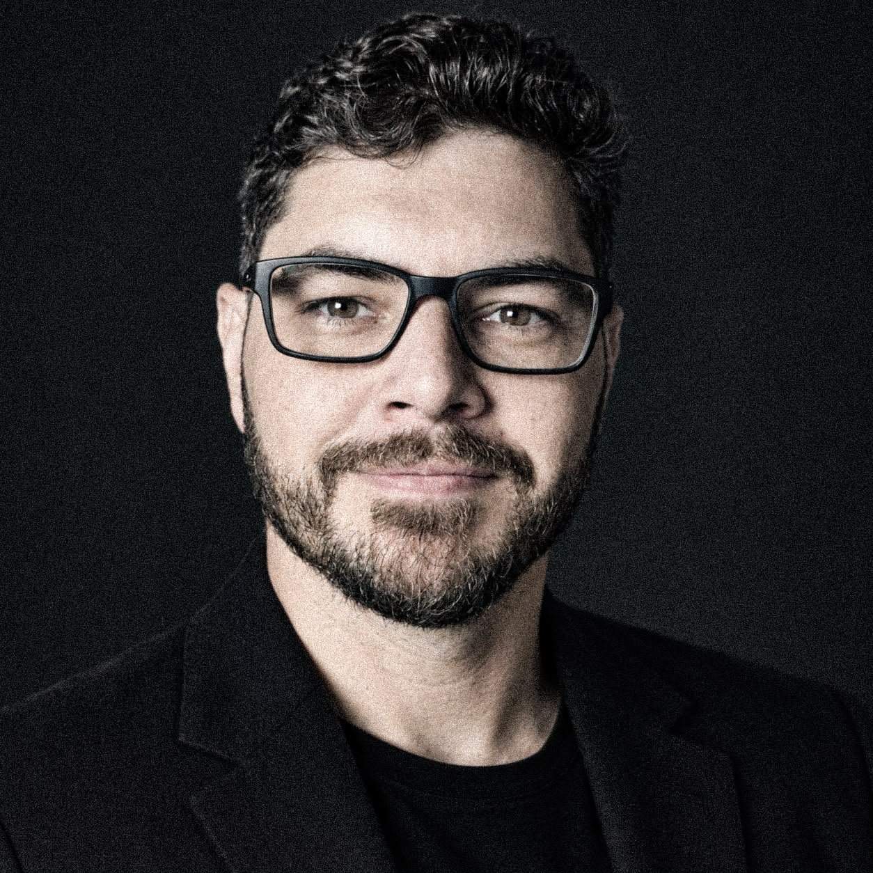 Caio Oliveira, de óculos e blazer preto